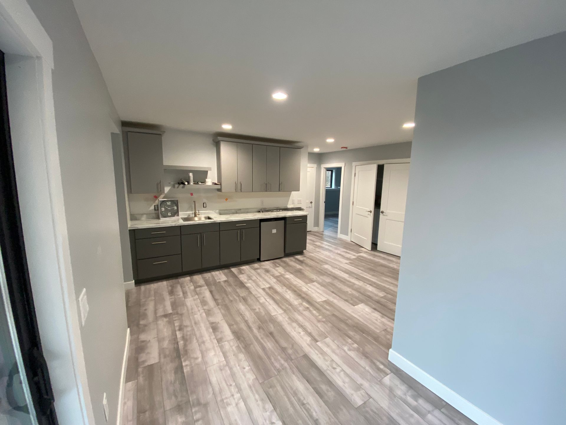 A kitchen with gray cabinets and a wooden floor.