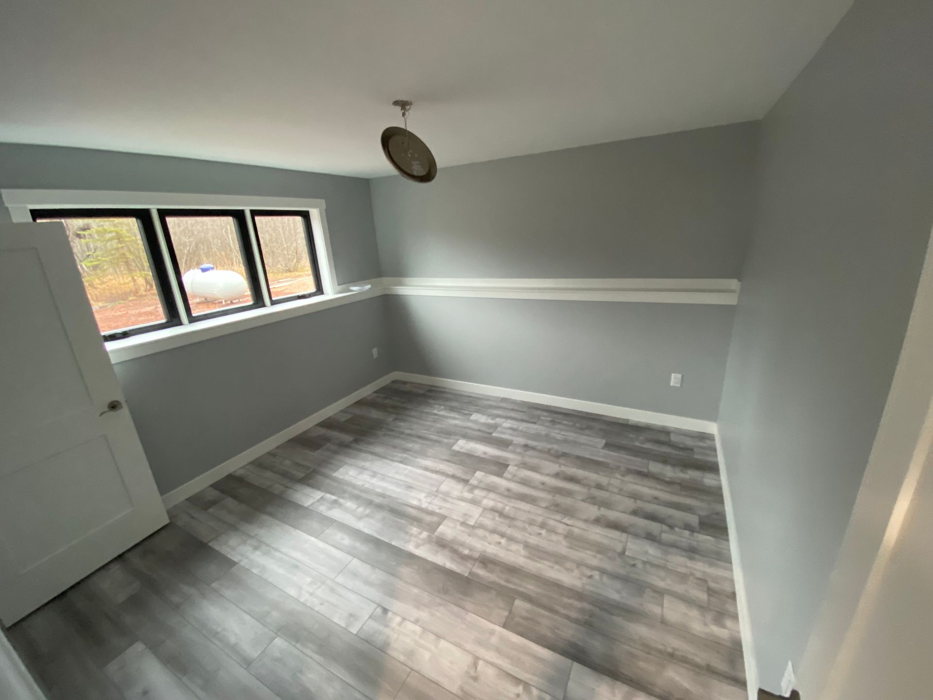 A room with a wooden floor and a clock on the ceiling.