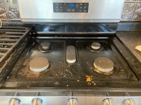 A dirty stove top oven is sitting on top of a counter in a kitchen.