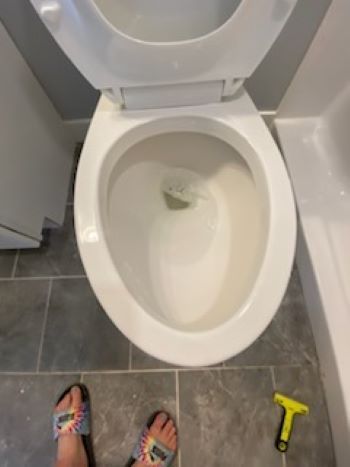 A person is standing next to a toilet with the lid up