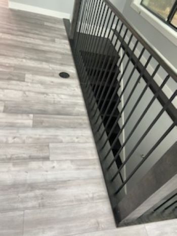 A staircase with a black railing and a wooden floor.