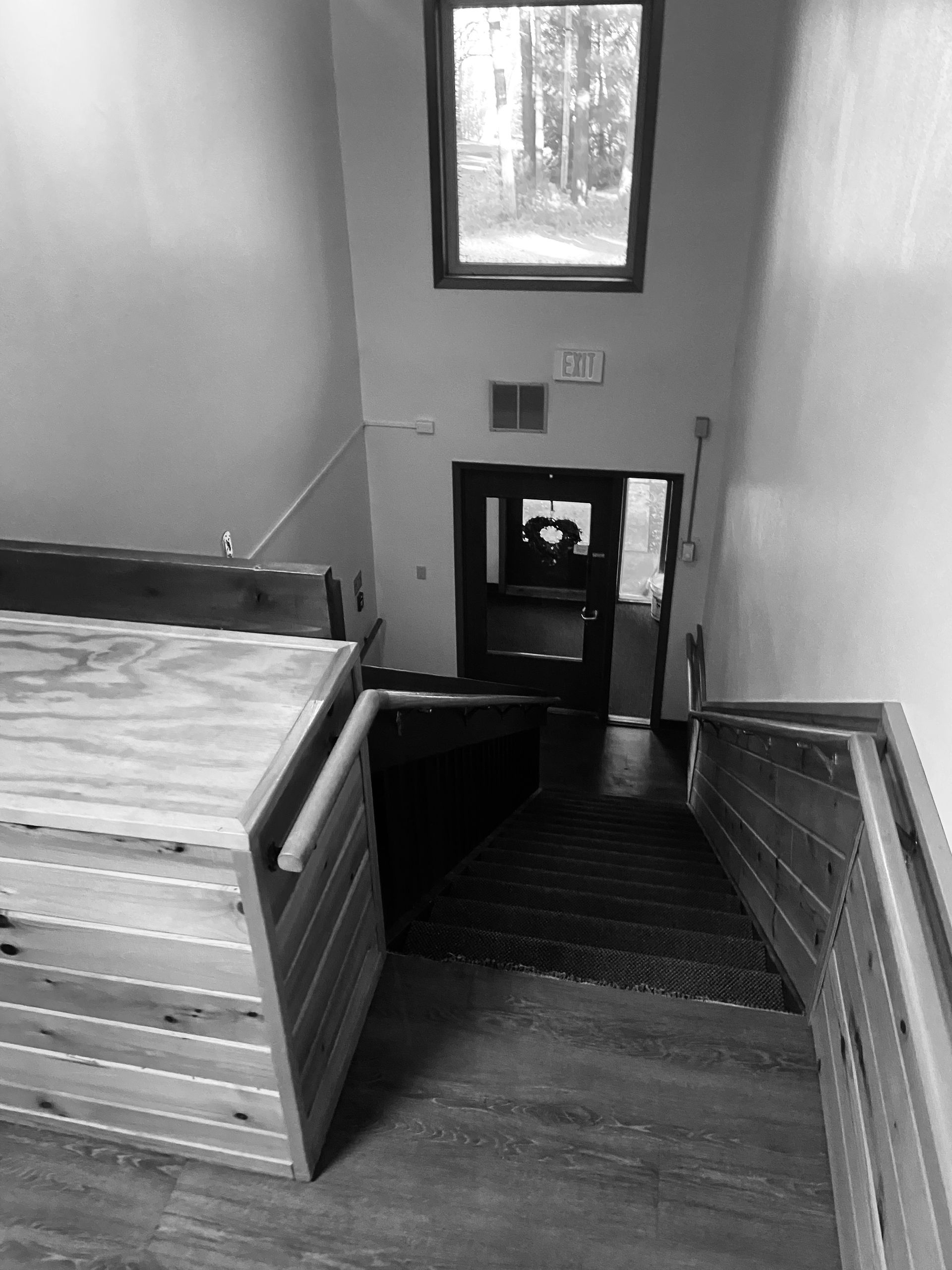 A black and white photo of a staircase leading up to a window.