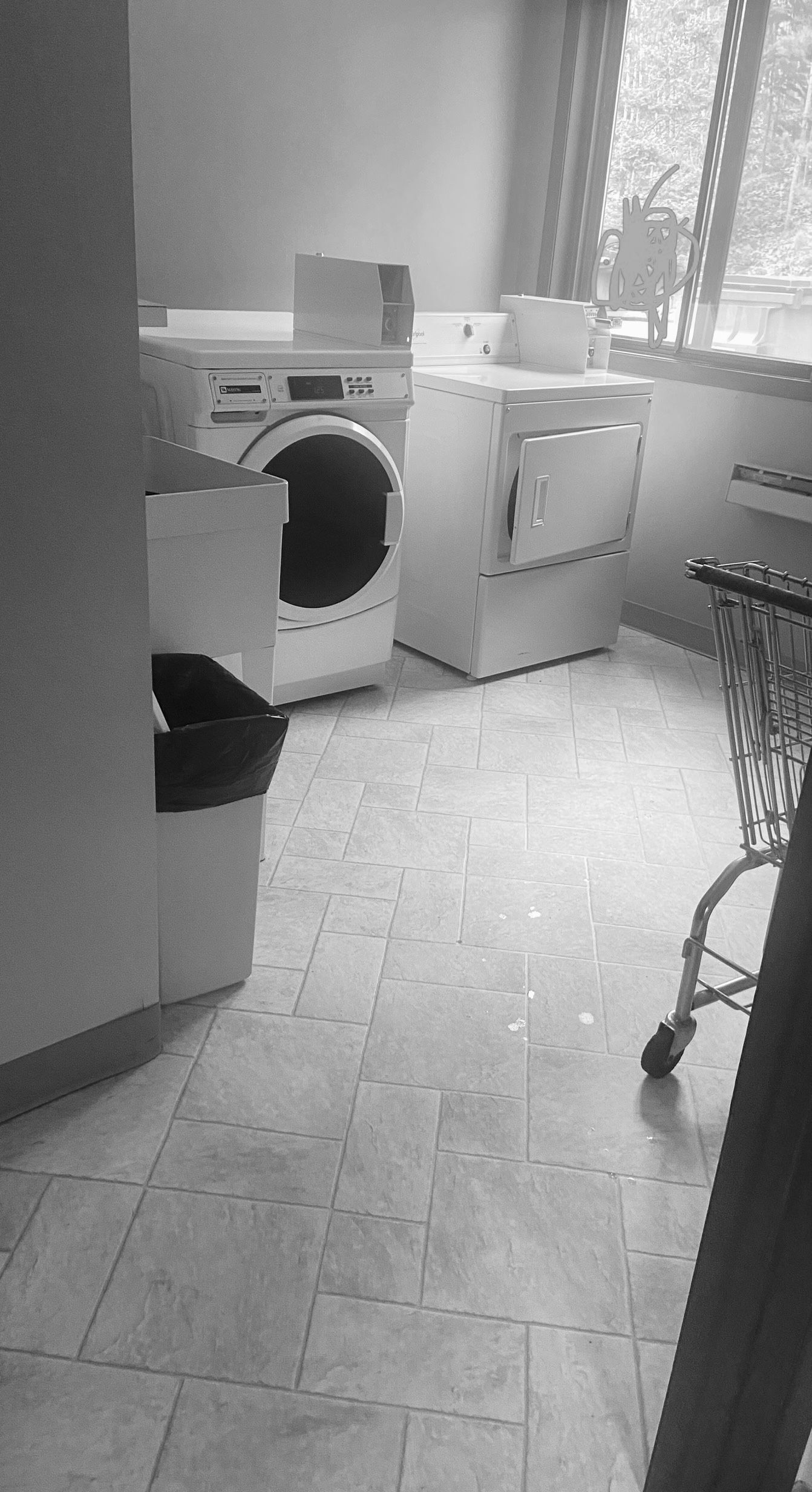 A black and white photo of a laundry room with a washer and dryer.