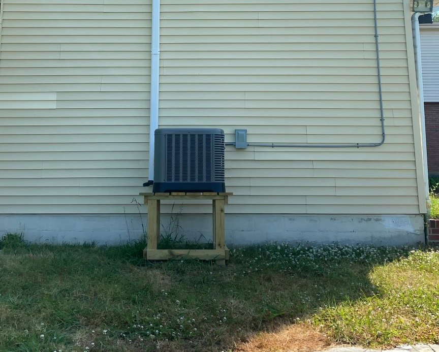 Electrician using a multimeter to inspect an air conditioning unit.
