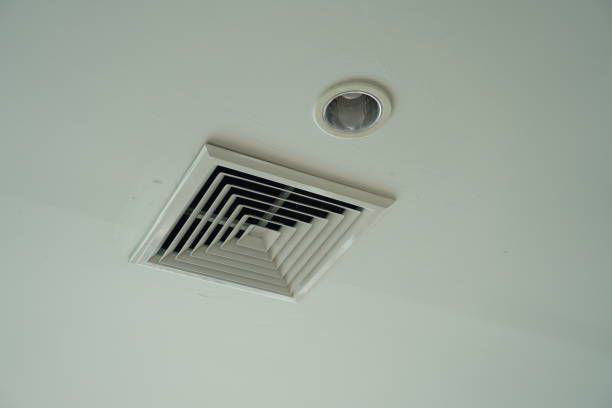 White ceiling with a square air vent and a round recessed light.