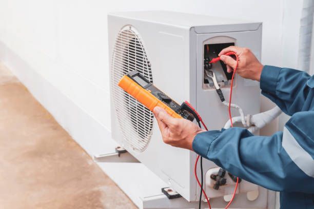 Electrician using a multimeter to inspect an outdoor air conditioning unit.