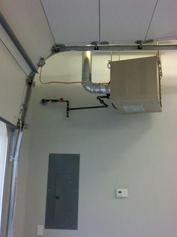 Garage interior with heater, ductwork, electrical panel, and door components.