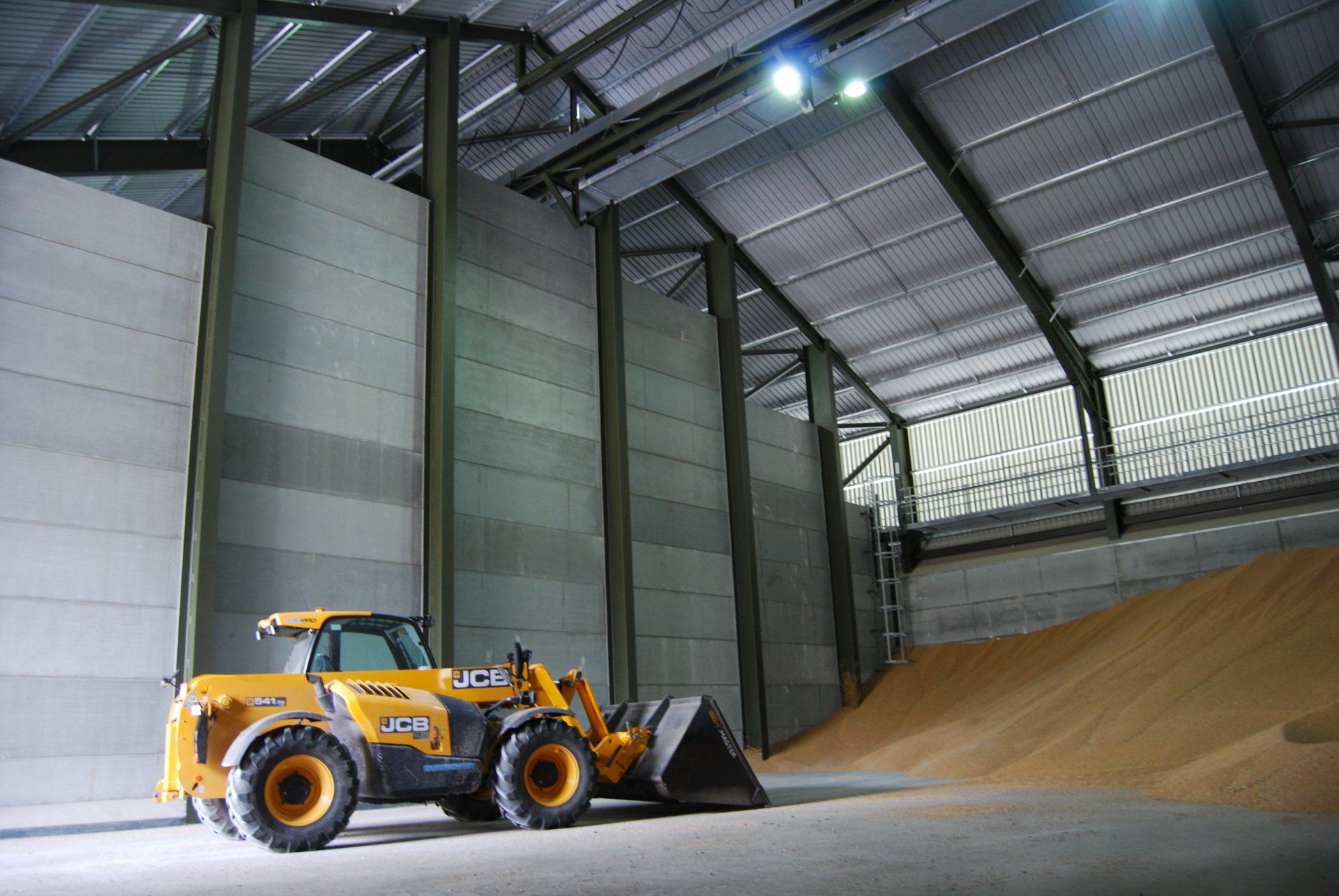 A yellow jcb tractor is parked in a large warehouse