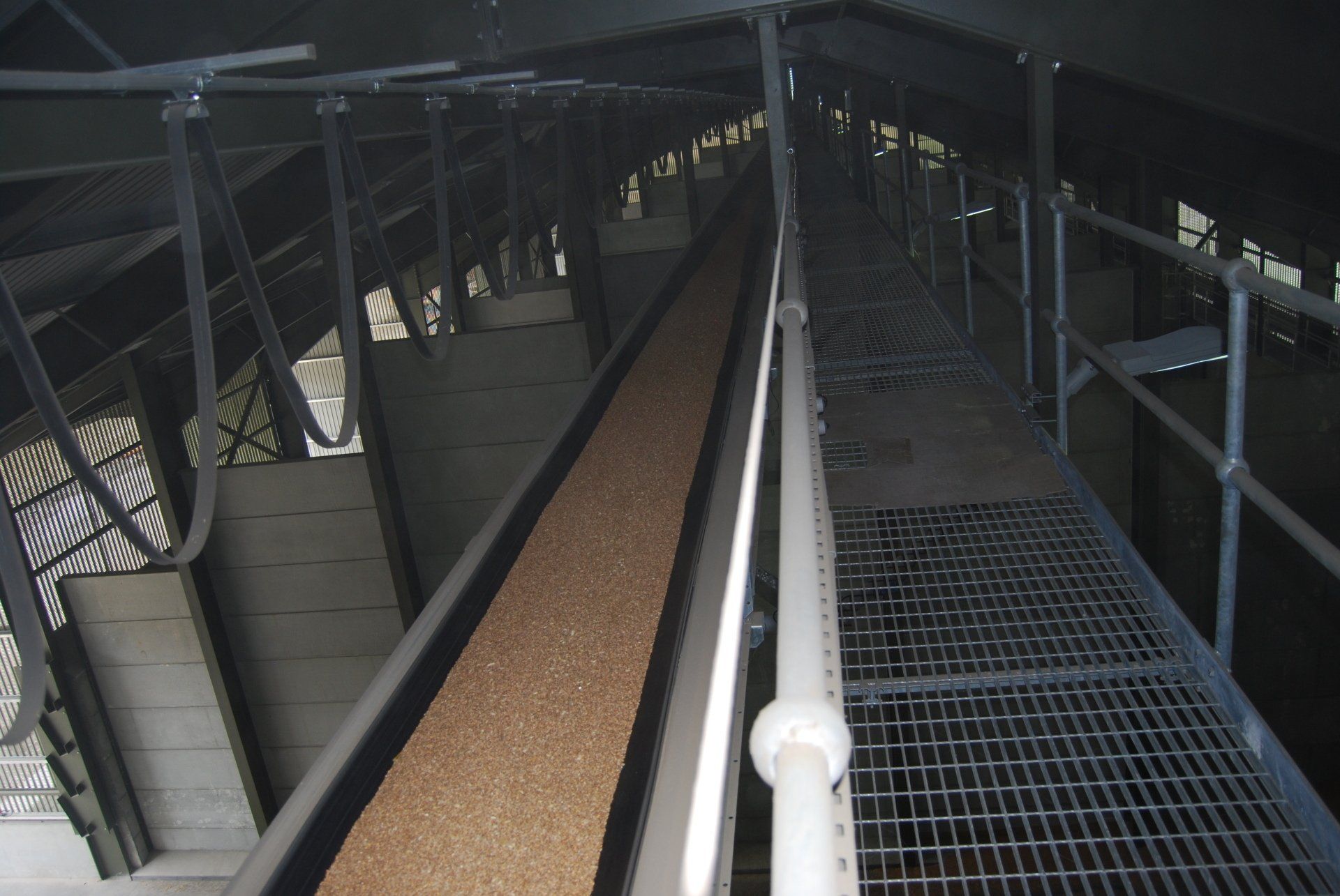 A conveyor belt in a building with a metal railing