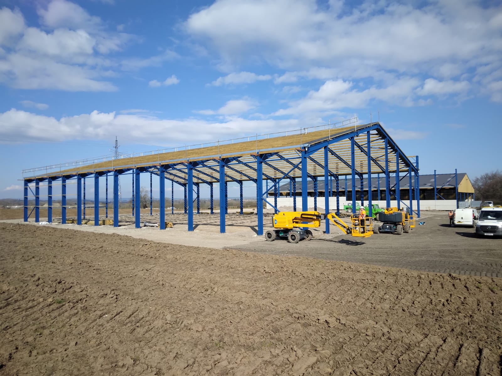 A large building is being built in the middle of a dirt field.