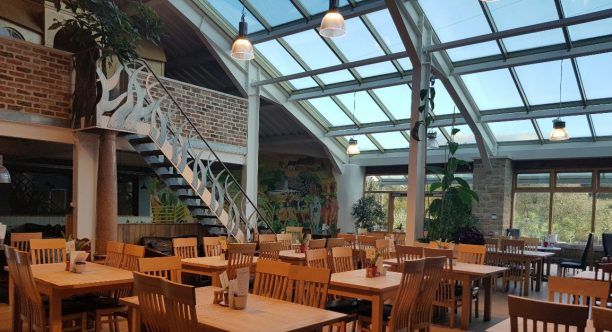 A restaurant with tables and chairs and a glass roof.