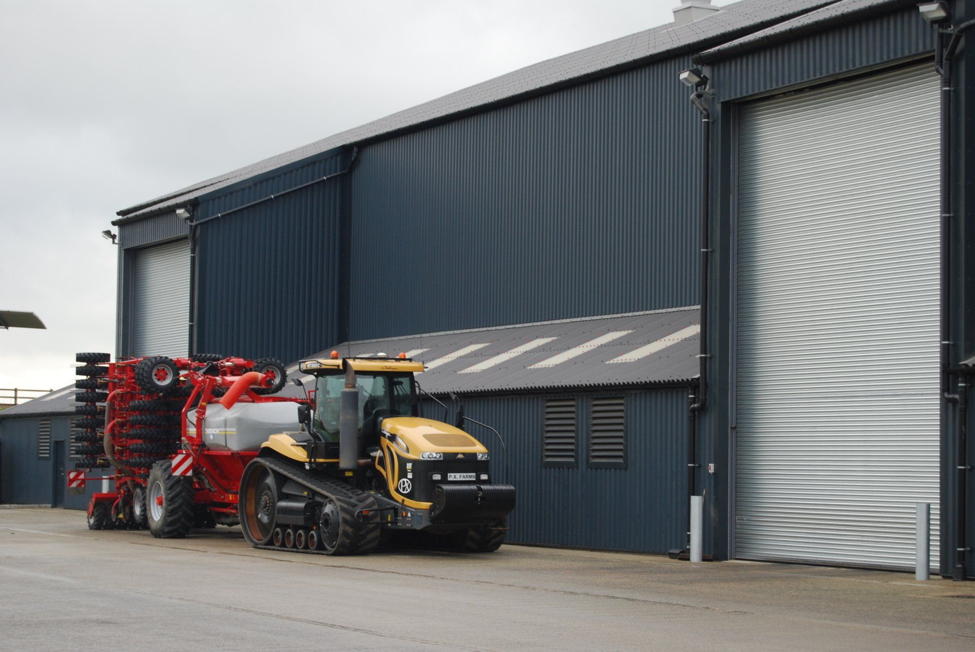 A yellow and red tractor is parked in front of a building.