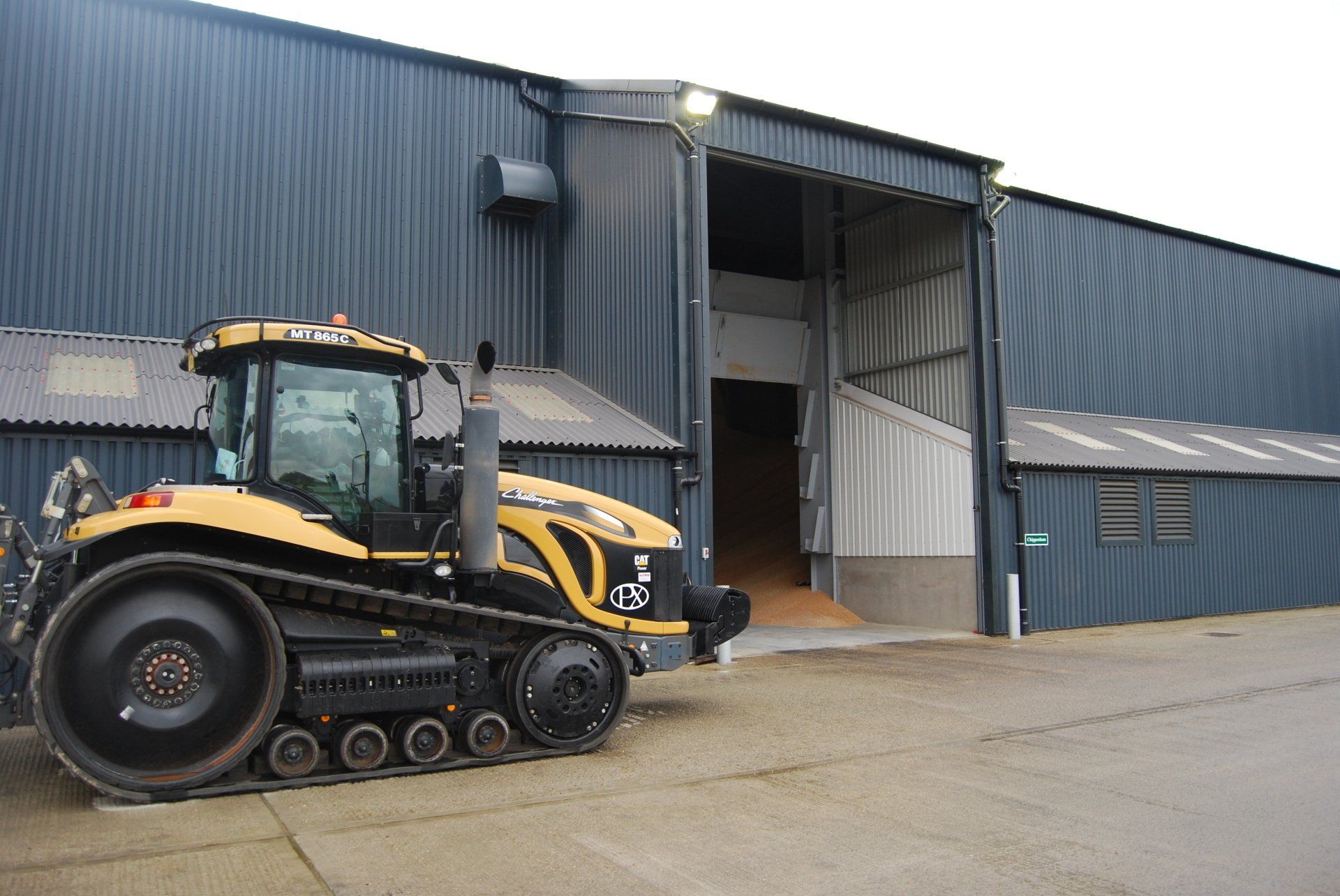 A yellow and black tractor is parked in front of a building.