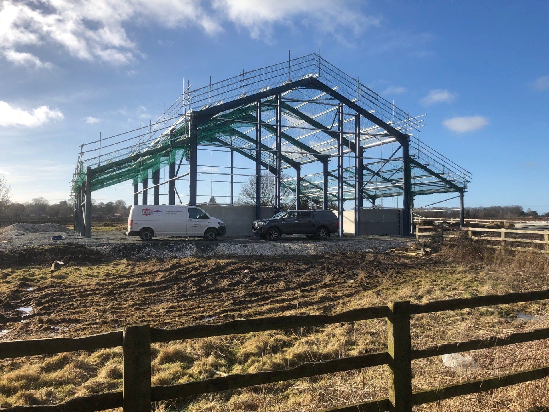 A white van is parked in front of a building under construction.