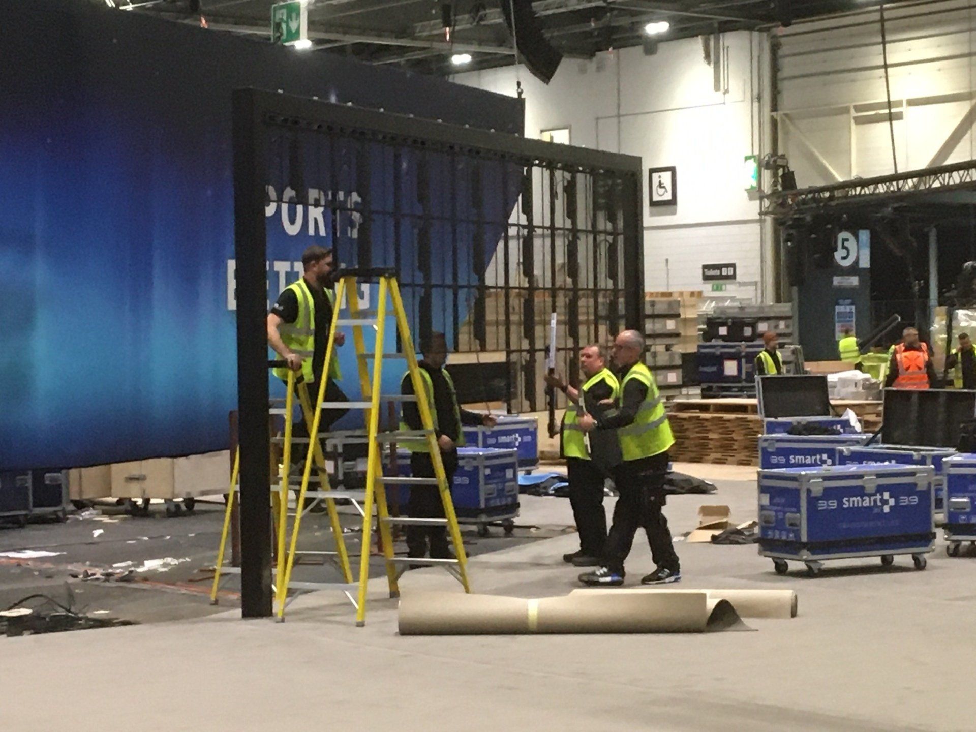 A group of men are working on a cage in a warehouse.