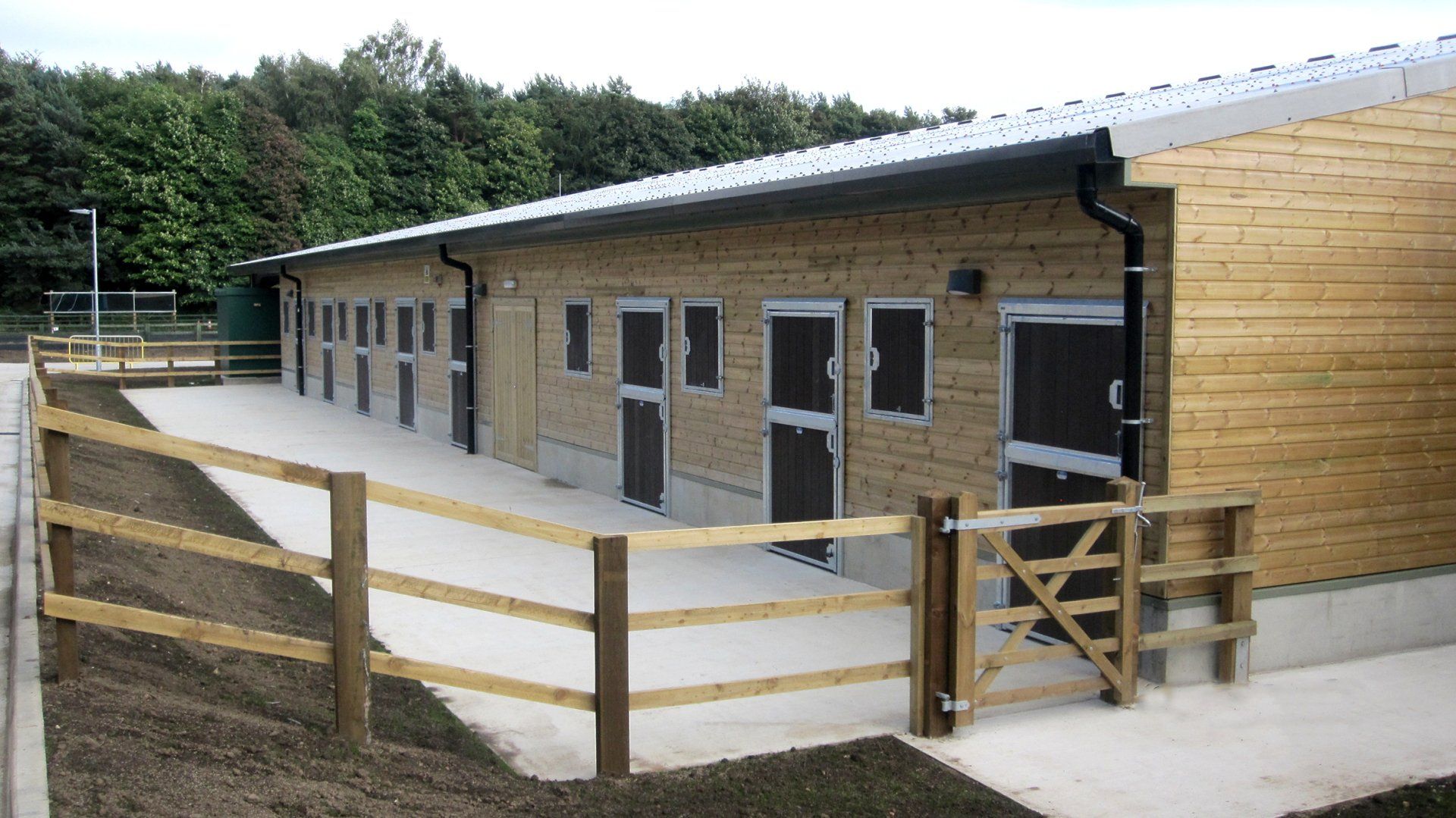 A row of stables with a wooden fence around them