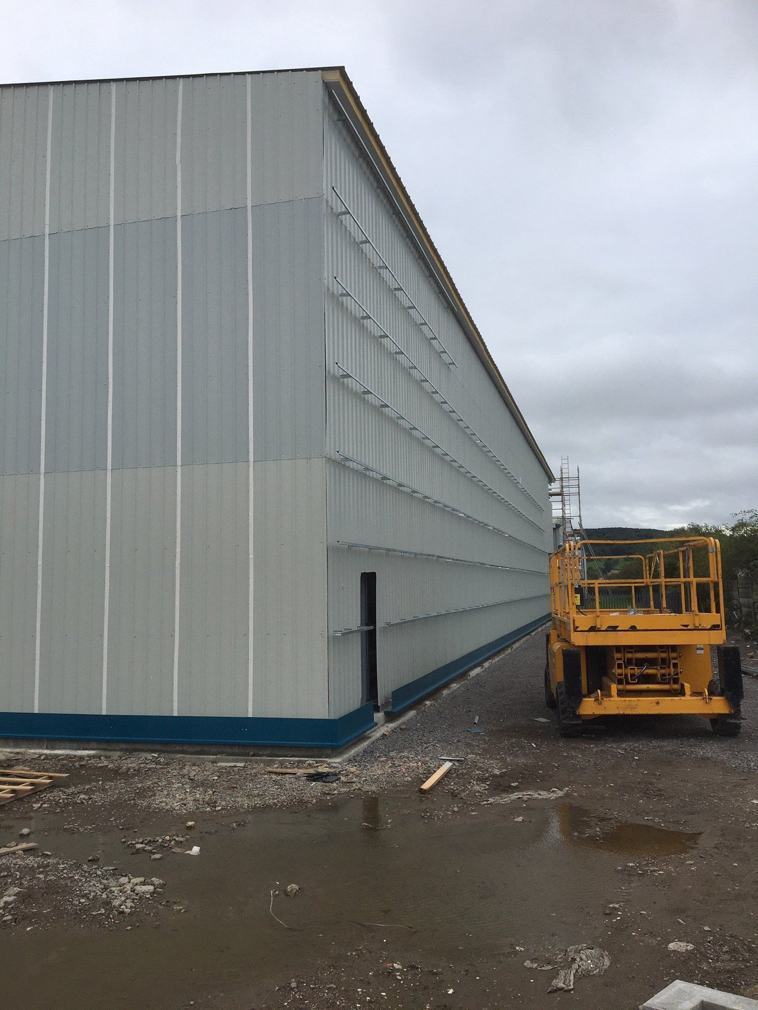 A yellow scissor lift is parked in front of a large building.