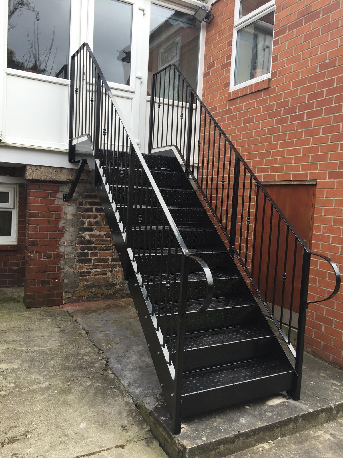 A set of black stairs leading up to a brick building.