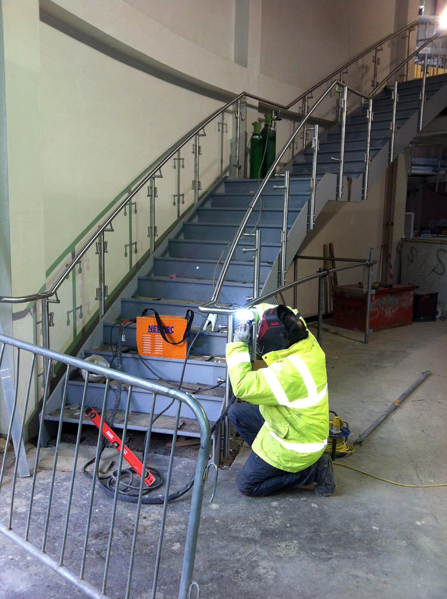 A man is welding a railing on a set of stairs