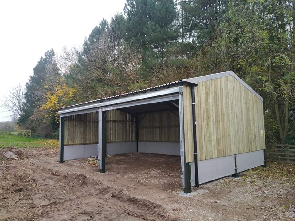 A large wooden building is sitting in the middle of a dirt field.