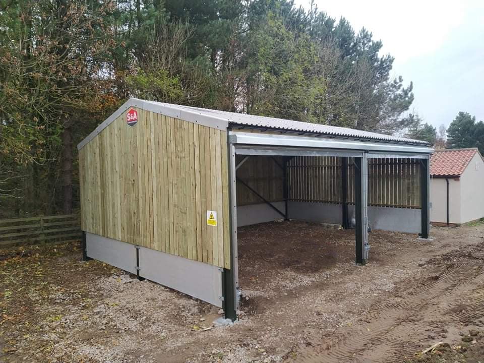 A wooden building with a metal roof is sitting in the middle of a dirt field.