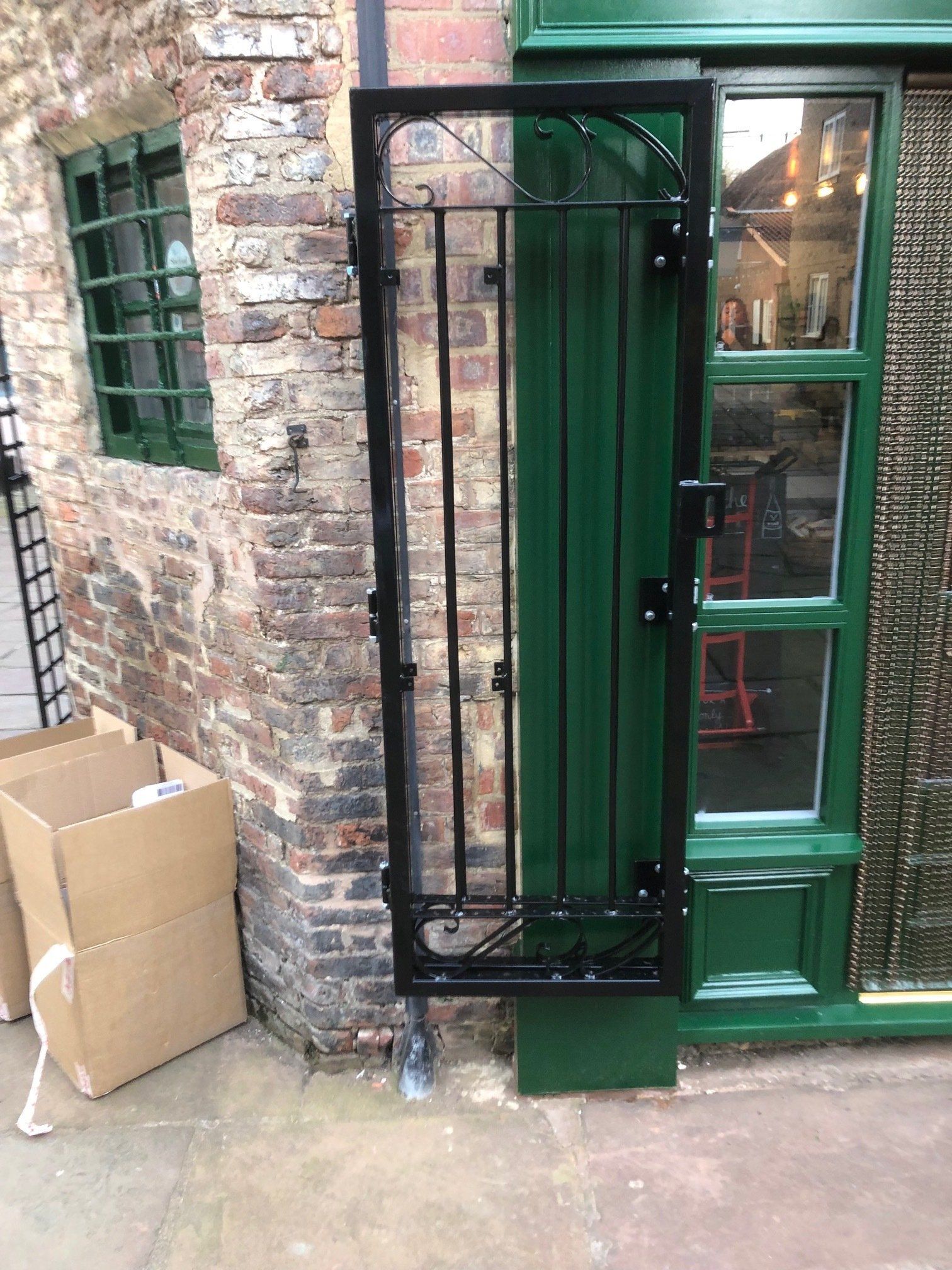 A black gate is sitting in front of a green door.