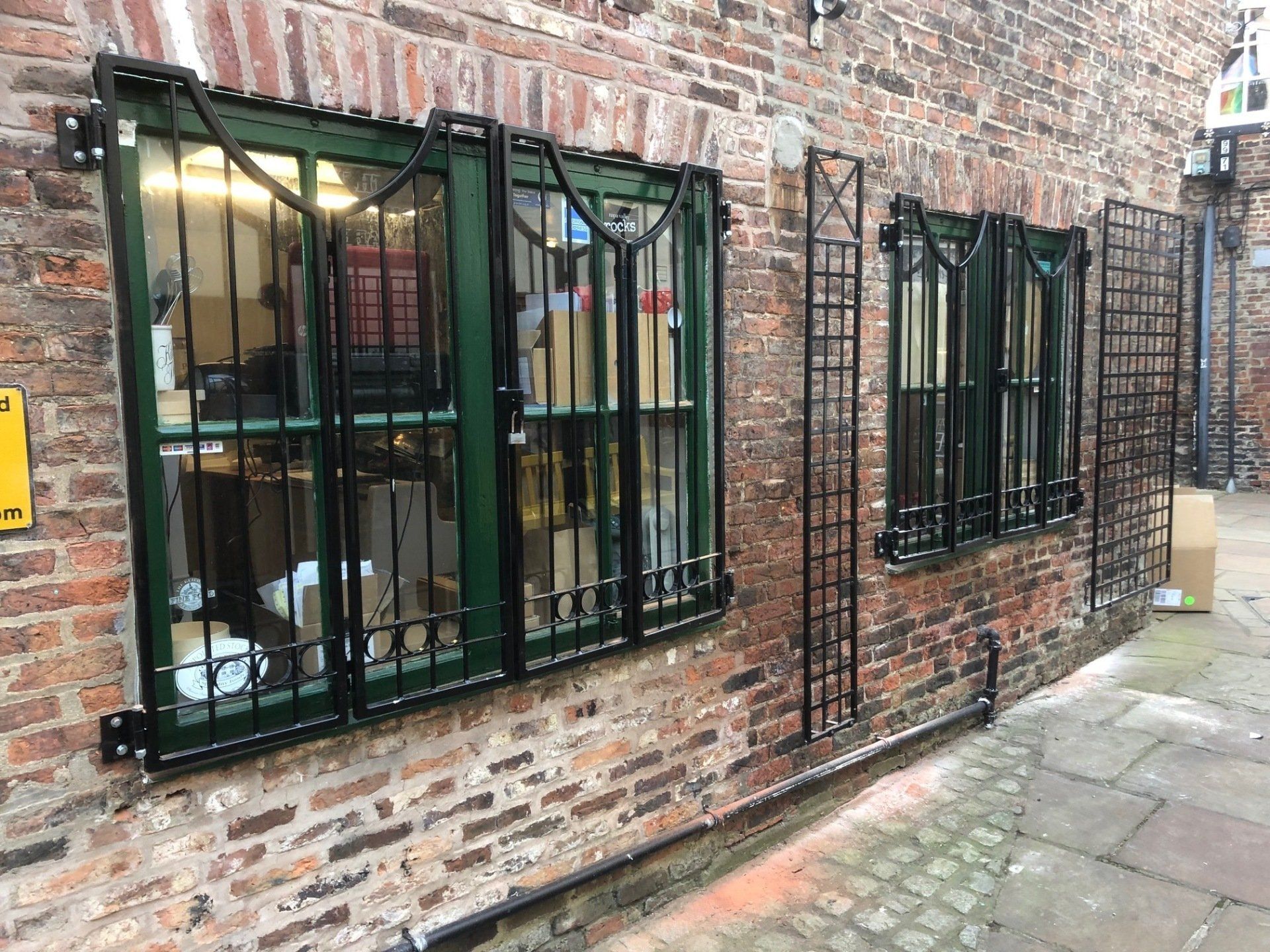 A brick building with a green window with bars on it.
