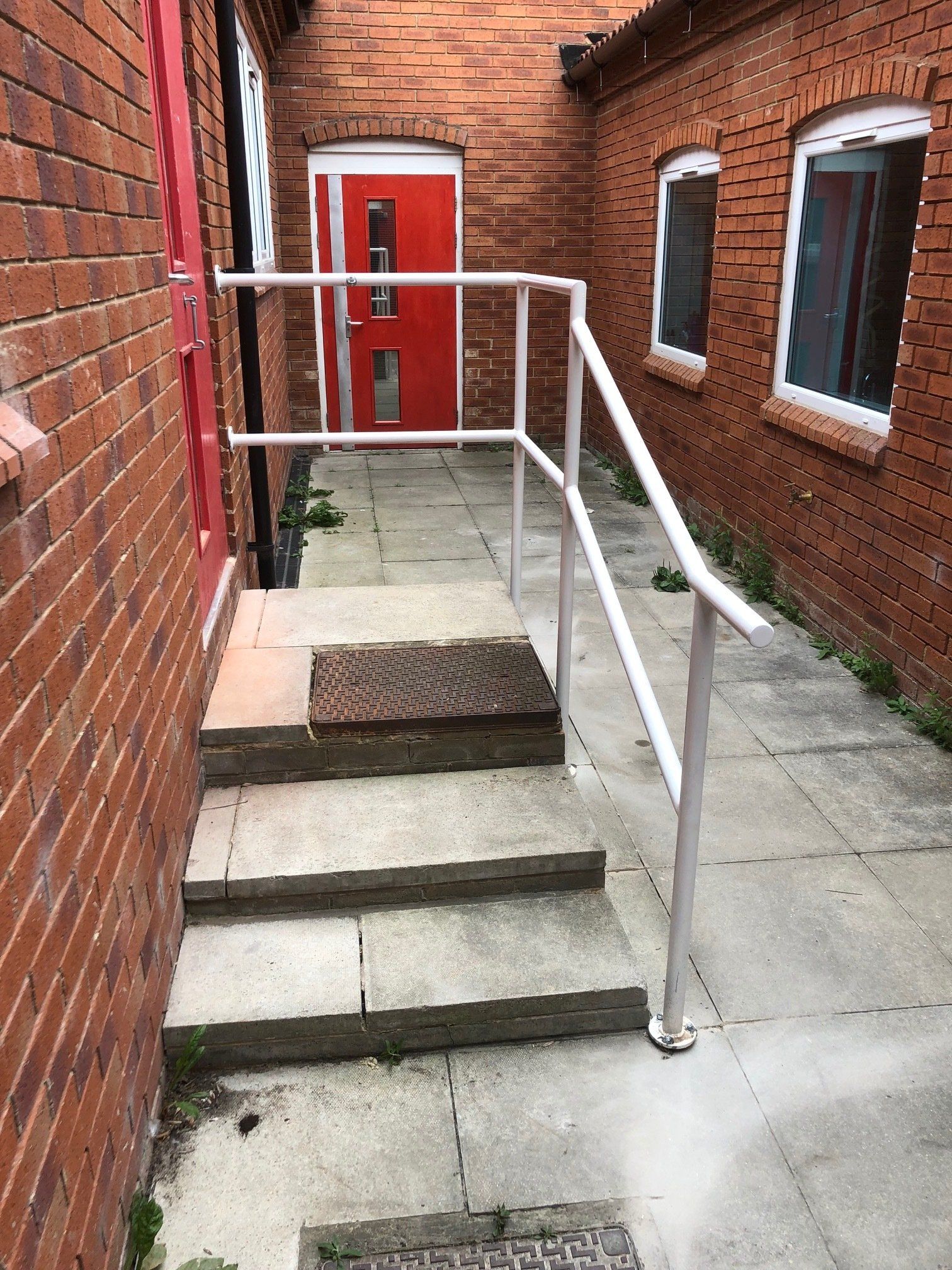 A brick building with a red door and stairs leading up to it.