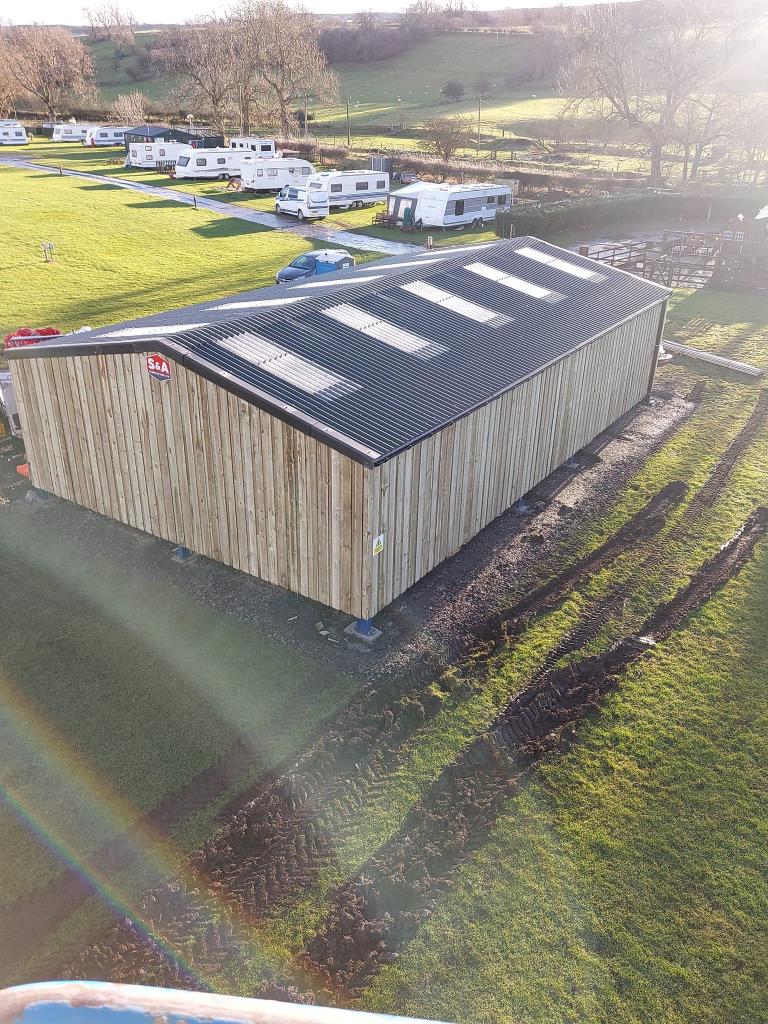 An aerial view of a large wooden building in the middle of a field.
