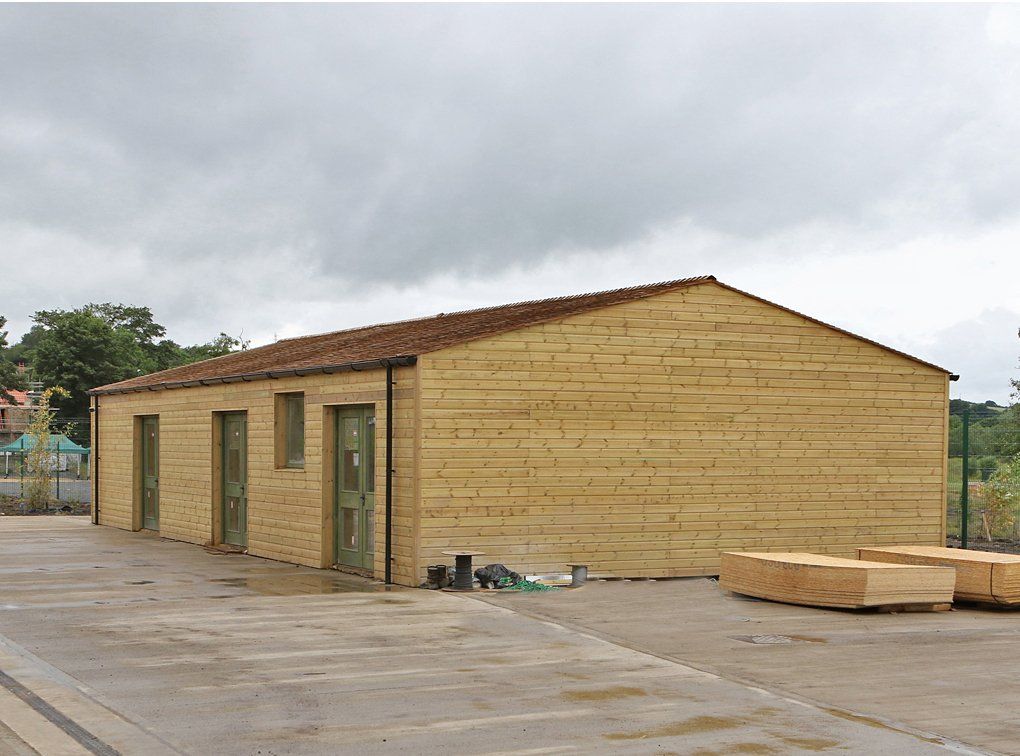 A large wooden building with a red roof is sitting in a parking lot.