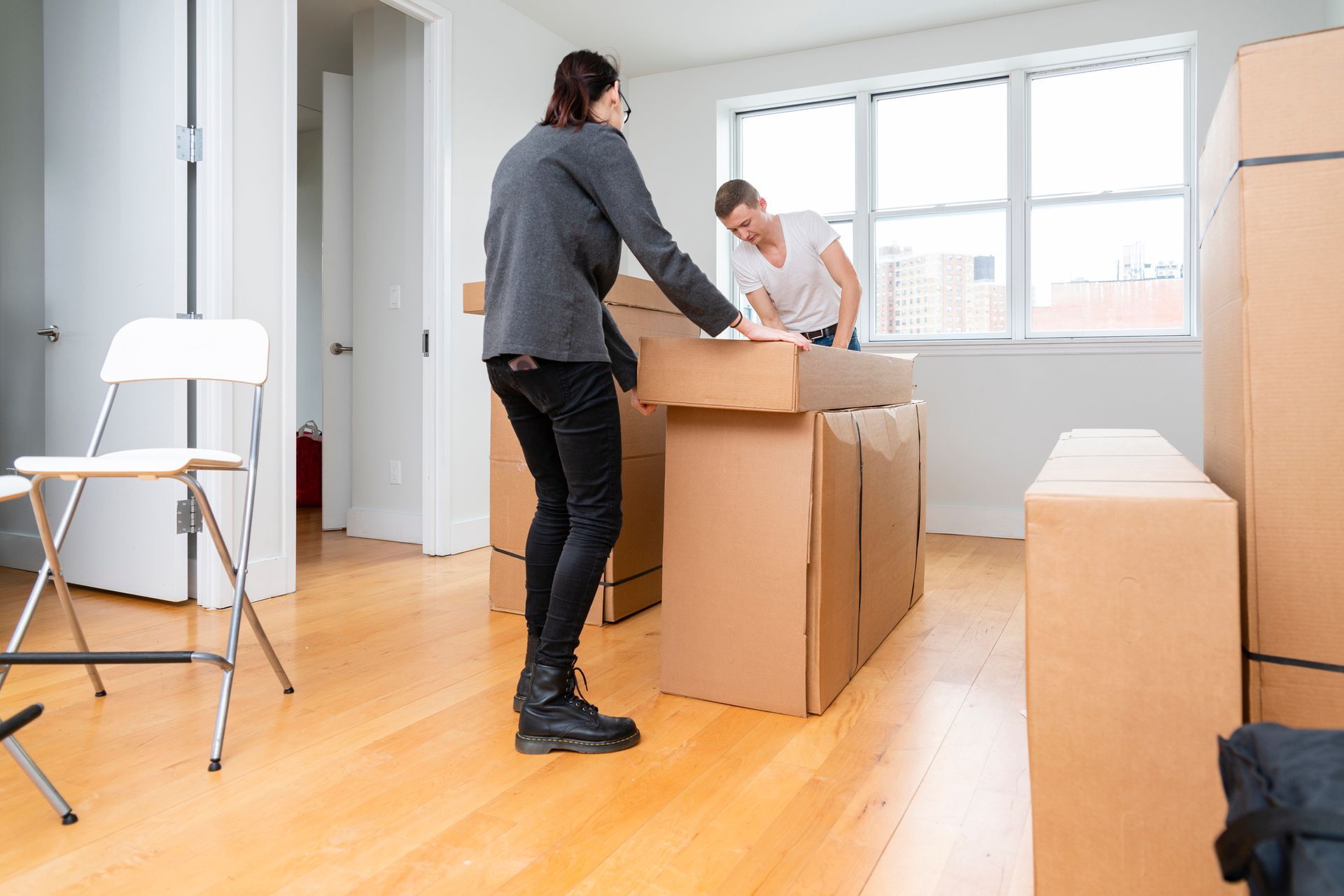 A Man And A Woman Are Packing Boxes In A Room | Clinton Township, MI | Touch of Class Cleaning