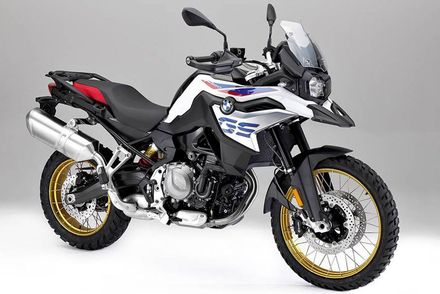 Una motocicletta bianca e nera è parcheggiata su una superficie bianca.