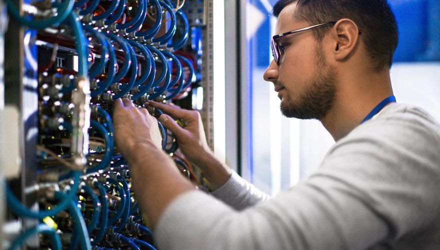 Man Connecting Cables In Server Cabinet — Kernersville, NC — Hodges Triad Electric Co LLC