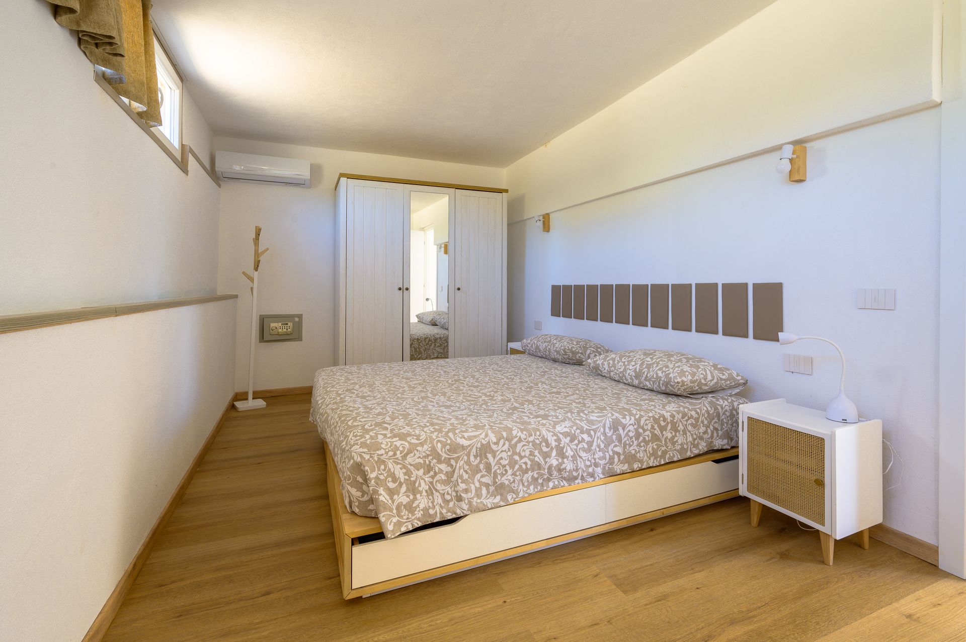 Camera da letto con letto matrimoniale, pareti bianche, pavimento e mobili in legno.