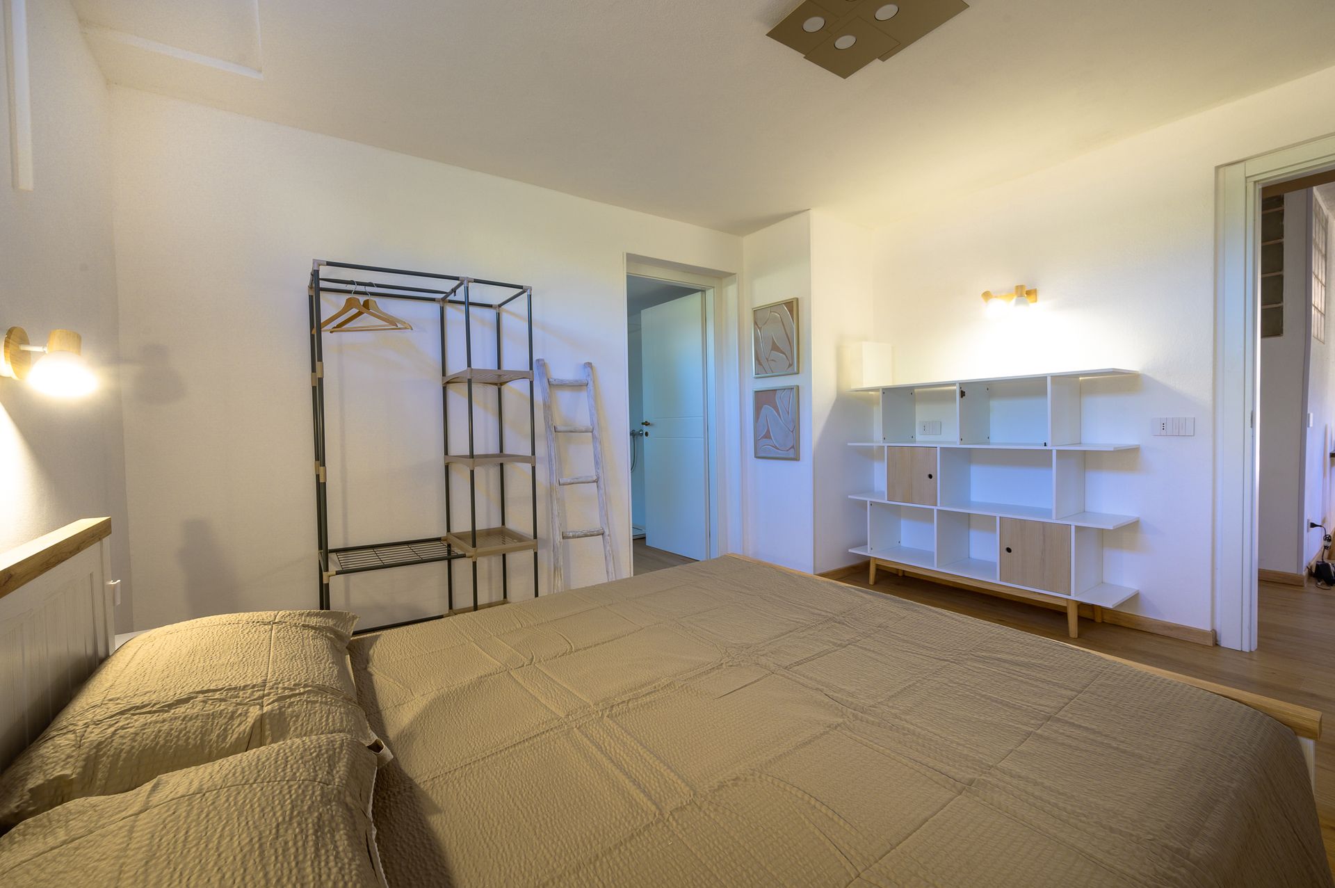 Camera da letto con letto, appendiabiti, scaffali e una porta.