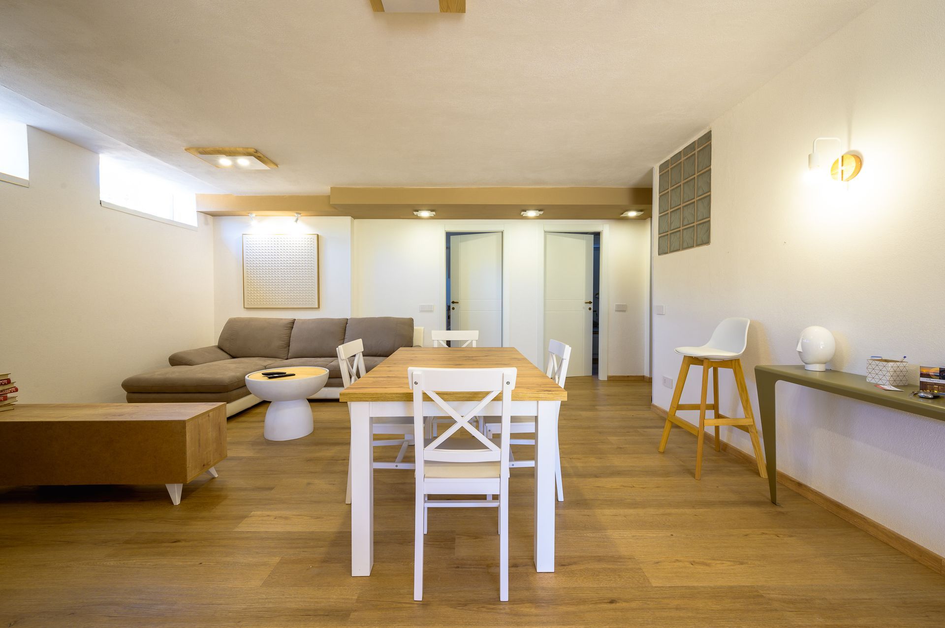 Uno spazio abitativo luminoso e moderno con tavolo da pranzo, divano e pavimenti in legno.