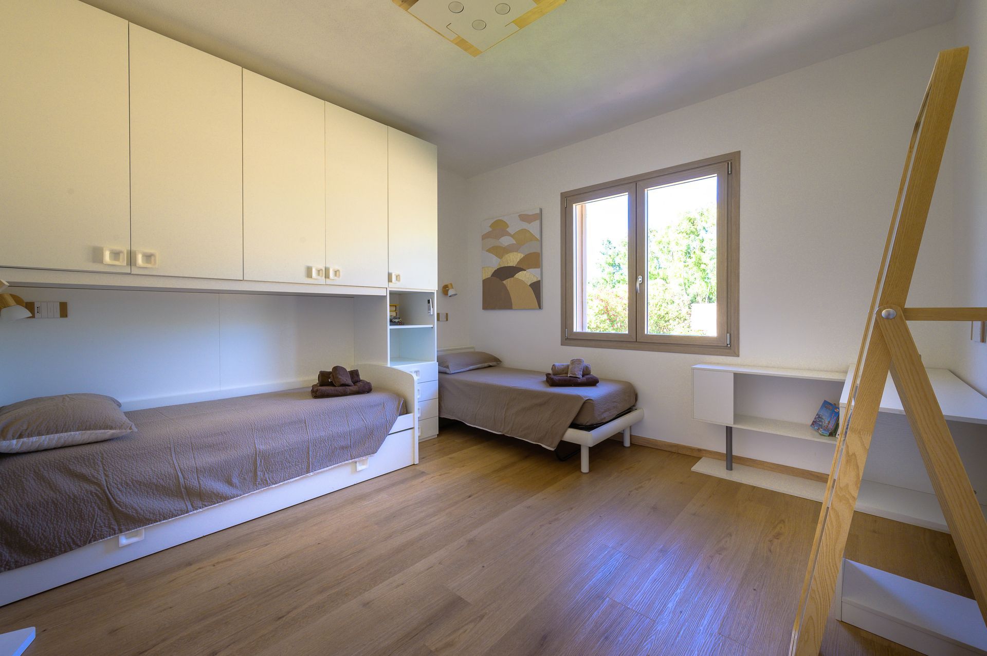 Camera da letto con due letti, pavimento in legno chiaro, ampio armadio a muro e finestra.