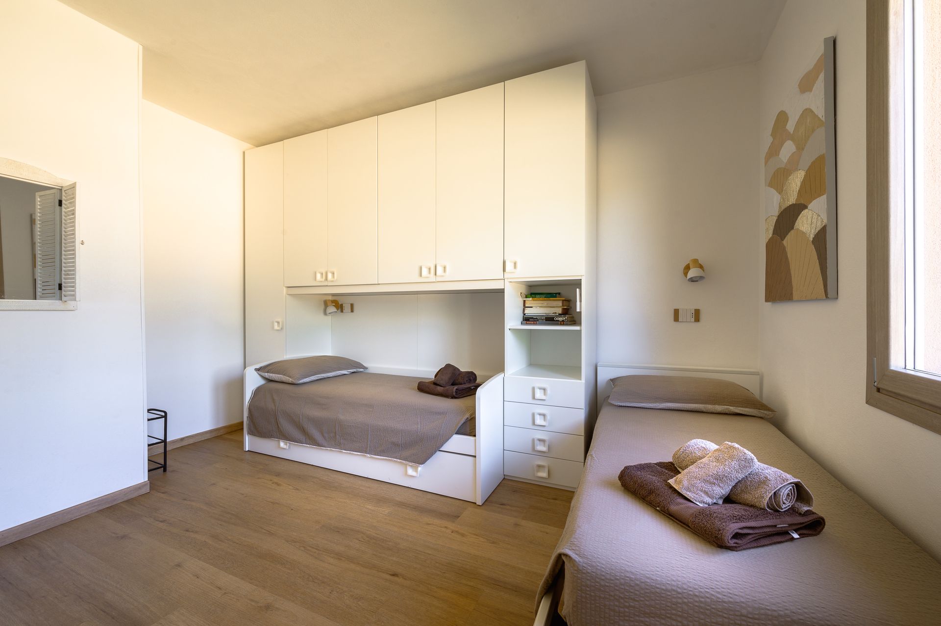 Una camera da letto con due letti singoli, un grande armadio e pavimento in legno chiaro.