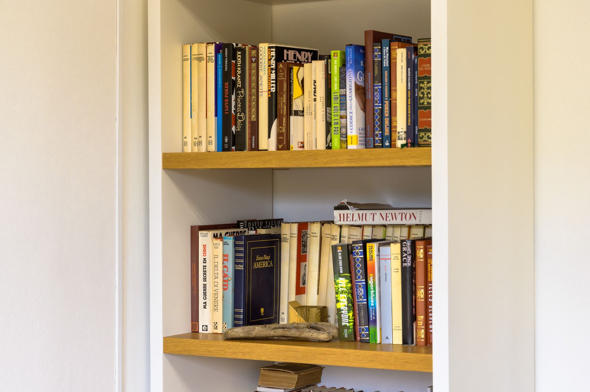 Librerie piene di libri di varie dimensioni e colori all'interno di un mobile bianco.