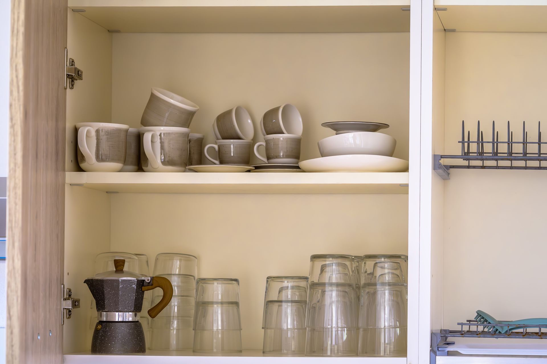 Mobile da cucina con tazze, tazzine, bicchieri, piatti e una macchina per caffè espresso da utilizzare sul fornello.