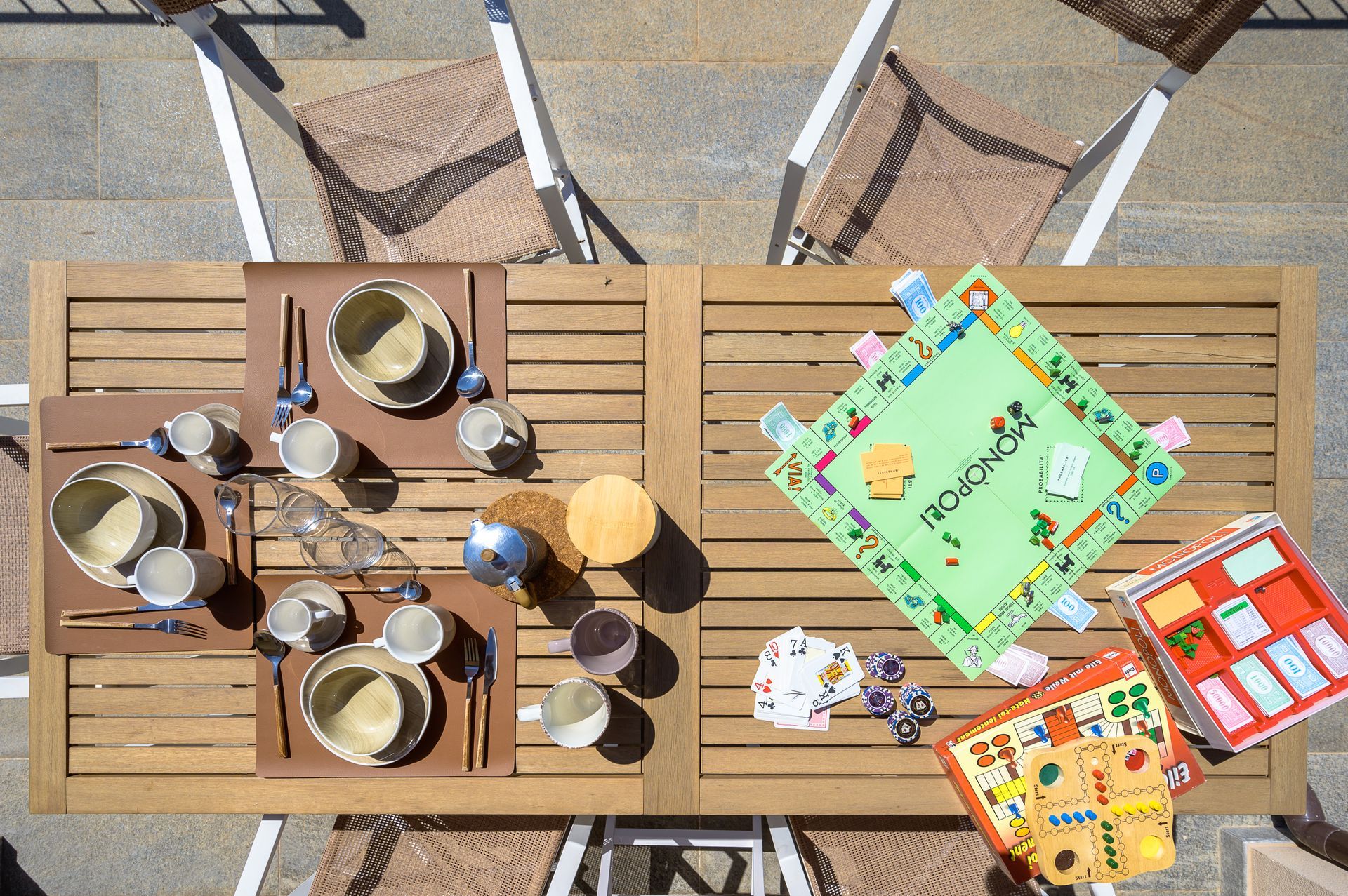Vista dall'alto di un tavolo di legno apparecchiato per due con piatti e un gioco da tavolo.