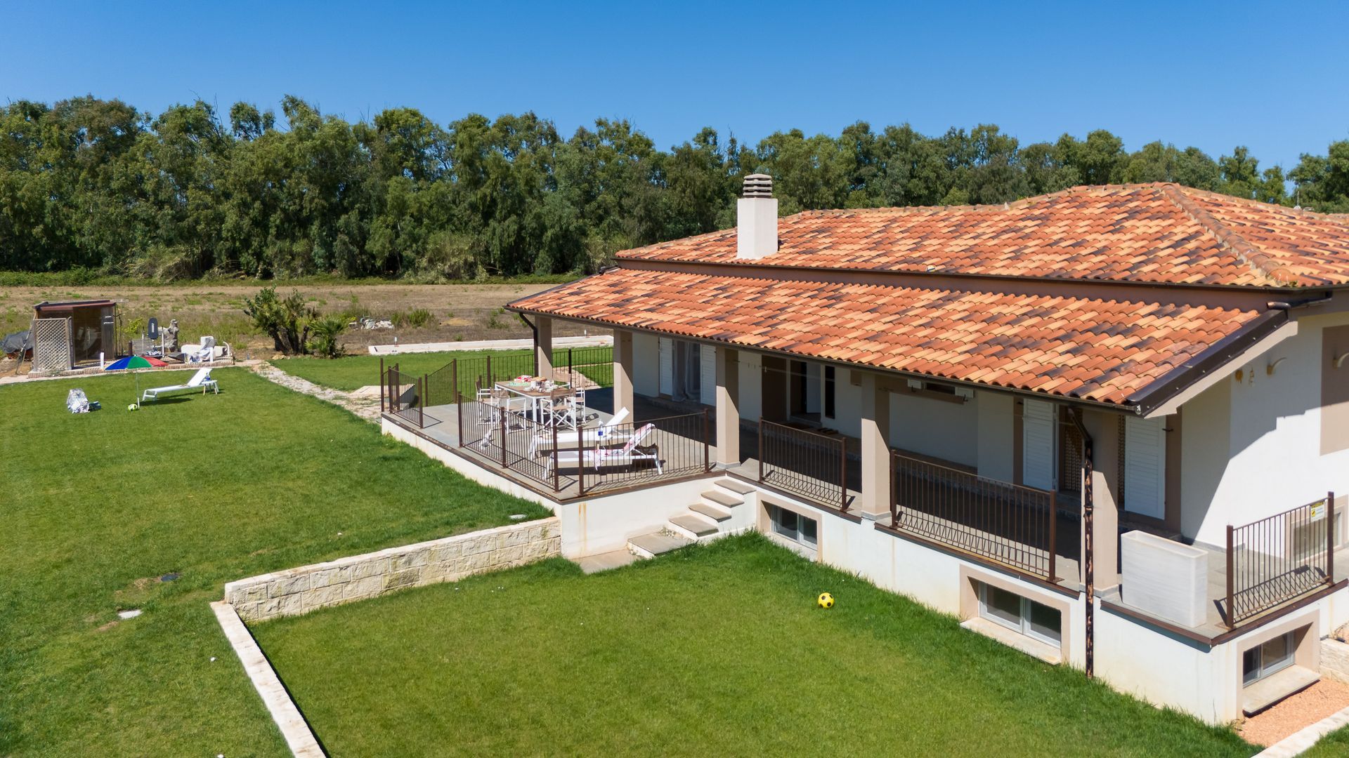 Una casa con tetto di tegole rosse e prato verde, in un ambiente esterno soleggiato.