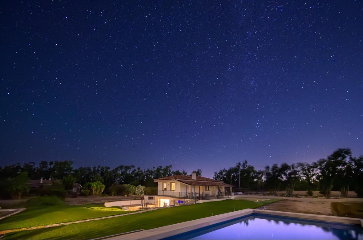 Cielo notturno sopra una casa con piscina, illuminato dalle stelle.