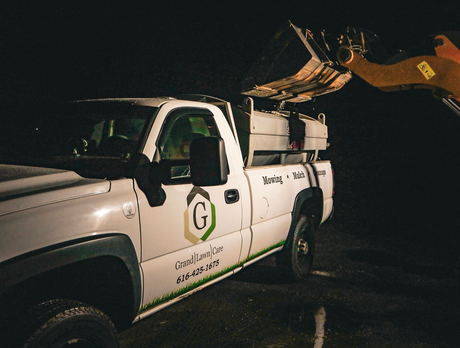 A Tractor is Plowing Snow in Front of a Garage