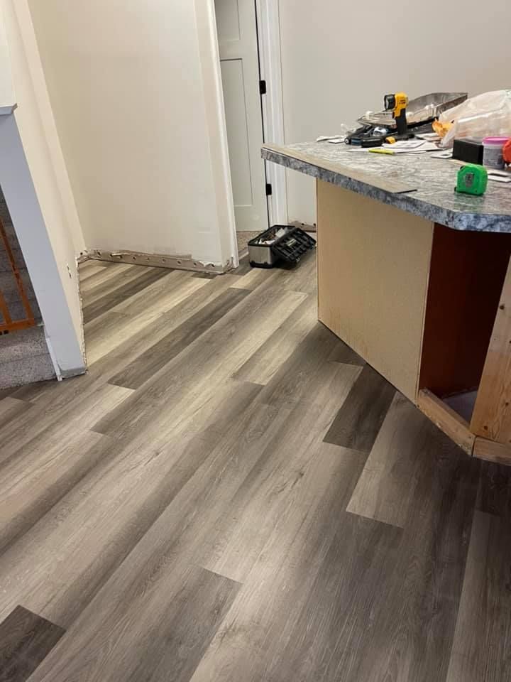 New gray wood-look flooring installed in a kitchen. A countertop with tools sits on the right.