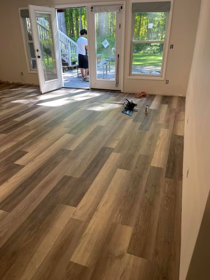 New wood-look flooring installed in a room with open doors to a deck and person standing outside.