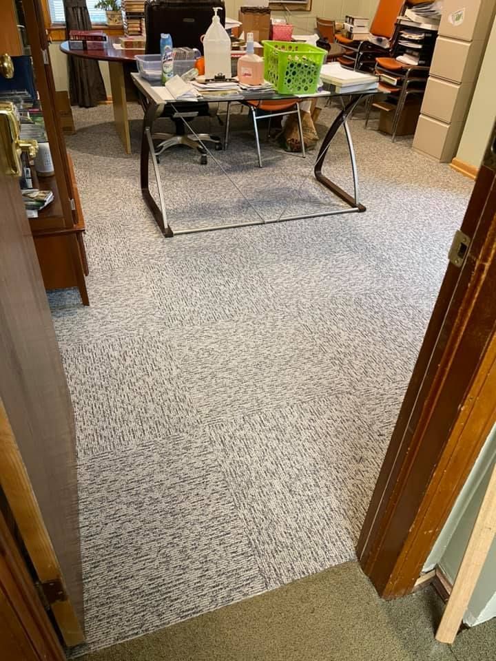 Office space with speckled floor, desk, and various supplies. Doorway on the side.