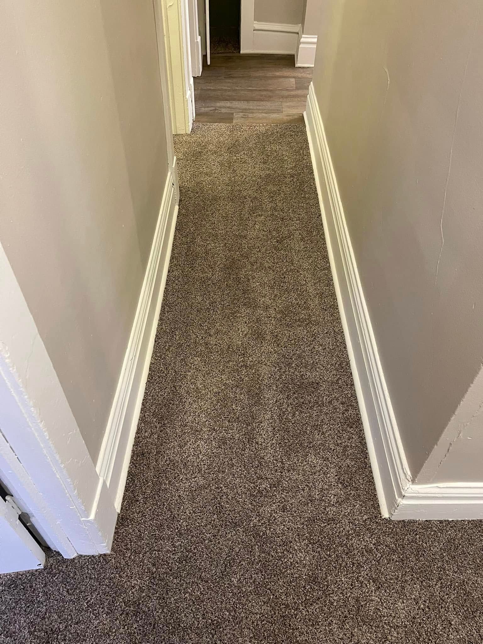 Narrow hallway with speckled carpet, white trim, and gray walls.