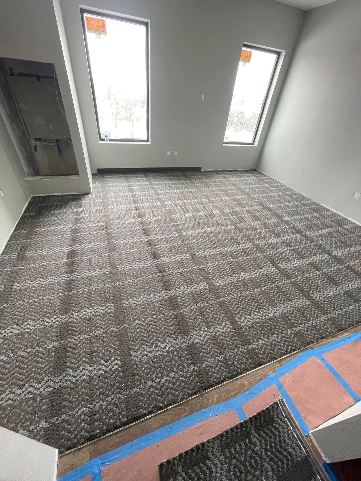 Room with grey carpet, angled ceiling, two windows, and a doorway opening.