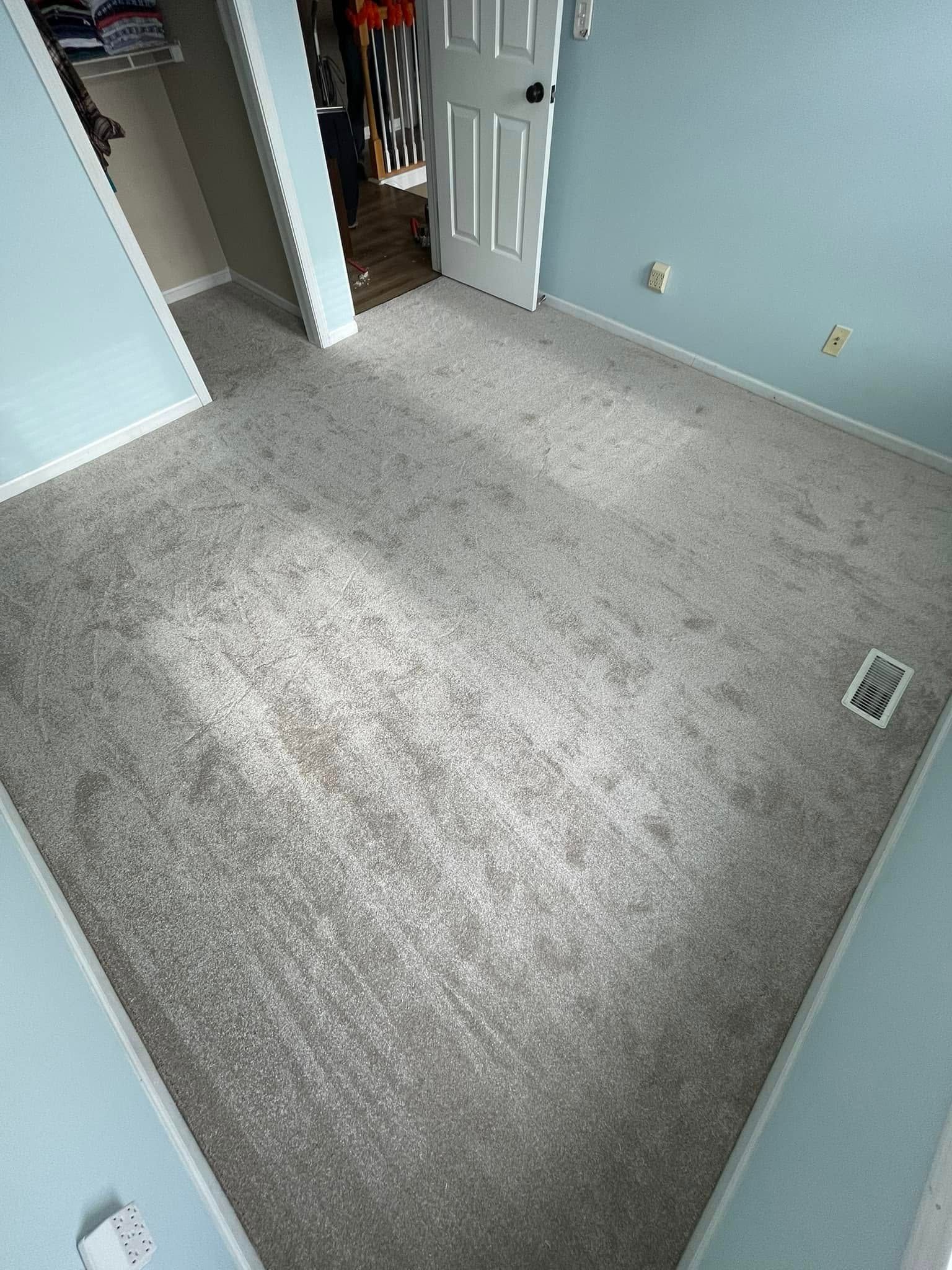Light gray carpet in a bedroom with pale blue walls and a white door.